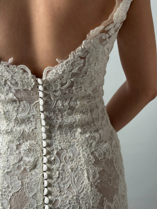 Open back detail of elegant mermaid lace wedding dress featuring floral lace and button closure for a romantic look.